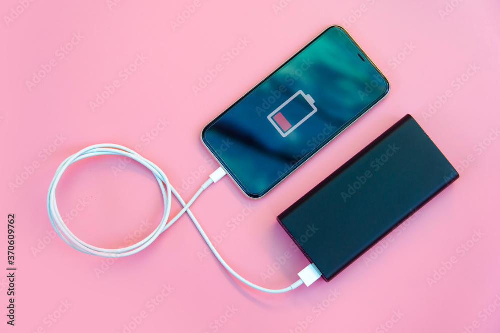 Smartphone charging with power bank on pink background. Flat lay 素材庫相片