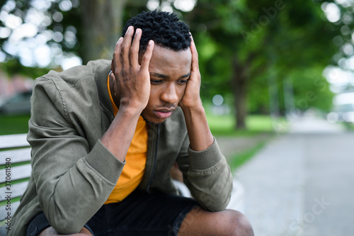 Frustrated young black man sitting on bench outdoors in city, black lives matter concept. © Halfpoint