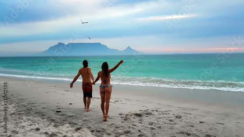 Young couple strolling on Cape Town beaches: Bloubergstrand and the view from Table Mountain photo