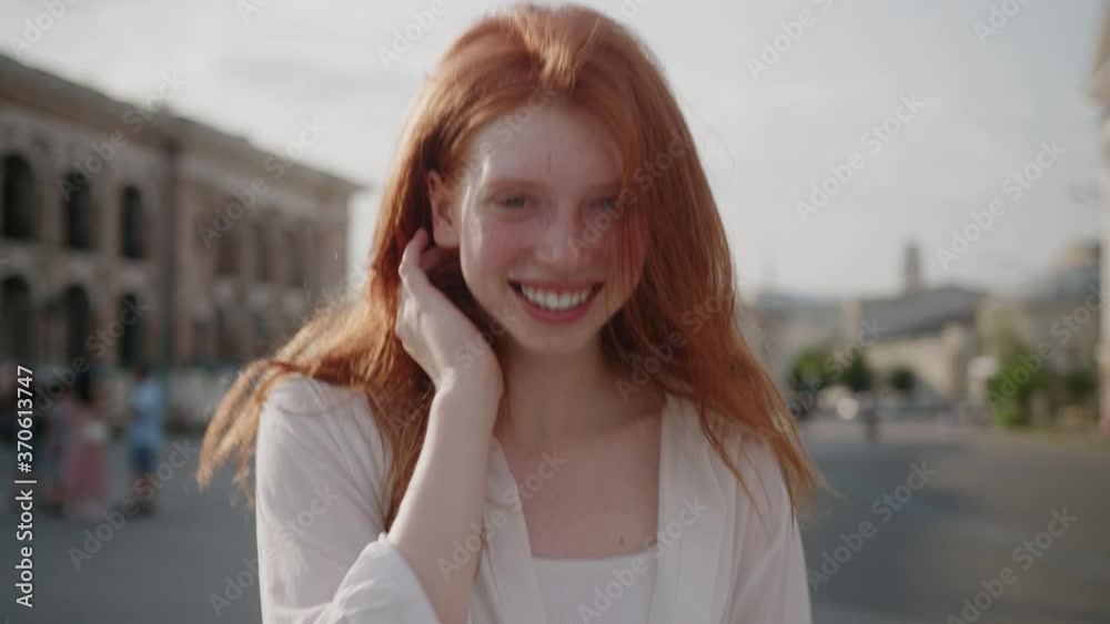 Close up young attractive woman with red hair turning look at camera smile walking in the city streets summer face beautiful lady portrait happy outdoor slow motion Close up young attractive woman with red hair turning look at camera smile walking in the city streets summer face beautiful lady portrait happy outdoor slow motion