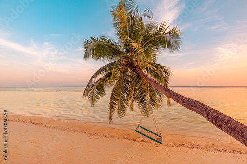 Tranquil summer vacation or holiday landscape. Tropical sunset beach view with palm over calm sea water and swing or hammock. Exotic nature view  inspirational and peaceful seascape reflection  sunset