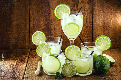 various cups and doses of caipirinha, typical Brazilian drinks, of lemon, with cachaça and sugar, on rustic wooden background, national caipirinha day, 13th September photo