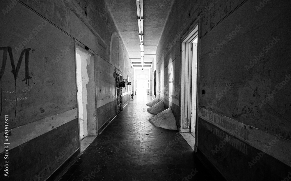 Antigo corredor abandonado com terra amontoada em cantos e parede com tinta descascando