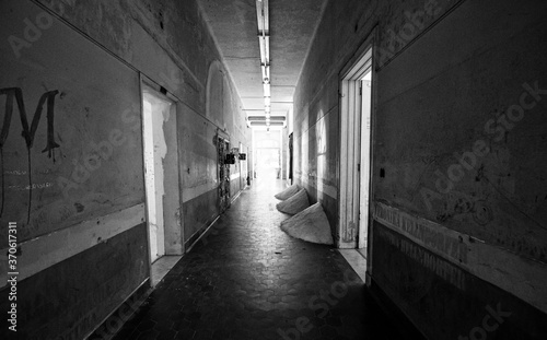 Antigo corredor abandonado com terra amontoada em cantos e parede com tinta descascando