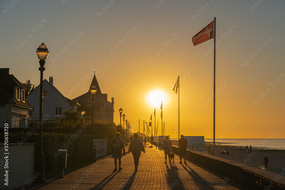 Langrune Sur Mer, France - 08 04 2020: People walking along the pear from the beach at sunset