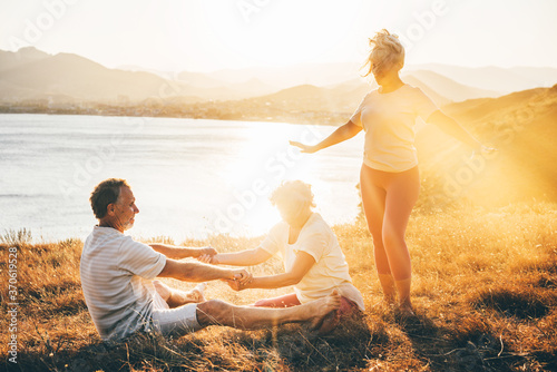 Senior woman helping to stretch senior couple while they doing workout and yoga exercices outdoors. Concept of healthy lifestyle.