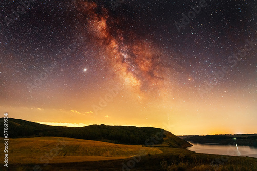Beautiful night landscape, starry sky with bright milky way galaxy above the lake.. Astronomical background.