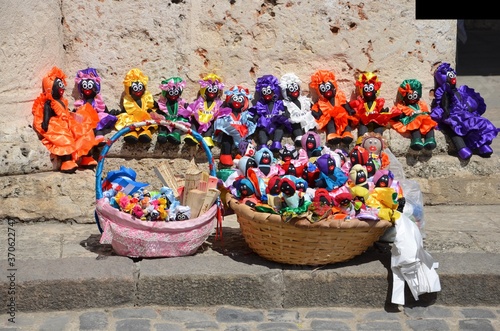 Photography Colorful dolls for sale on a street market in Havana, Cuba, stone wall in the ba