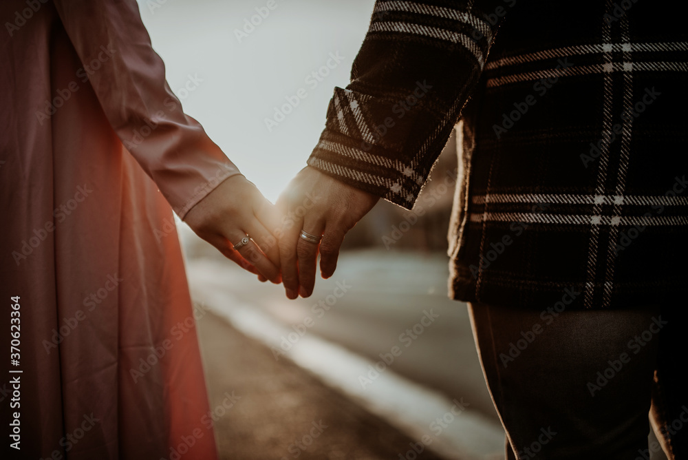 Fototapeta premium Interracial couple, man and woman holding hands, one wearing a gold wedding ring.