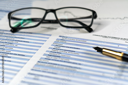 Balance sheet in stockholder report book with glasses, balance sheet is mock-up. Investment analysis for portfolio