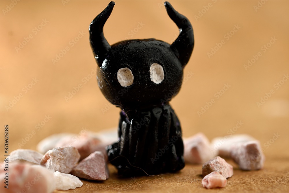 Obraz premium Action figure characterizing a shadow, made of black plasticine, around stones, all placed on recycled paper