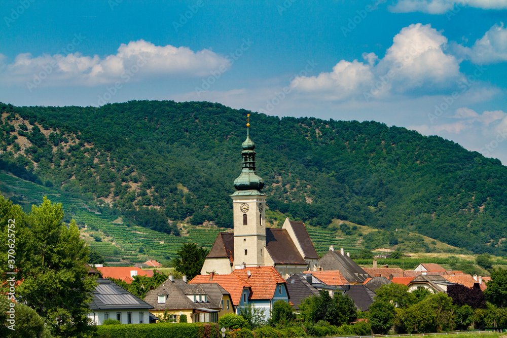 A church with clock tower in the wine region near Durnstein, Austria  A vineyard in the background.