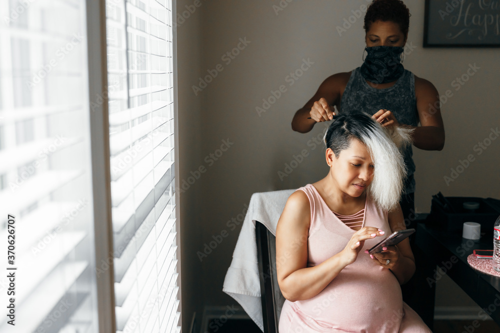 Pregnant black woman having hair done and selfcare by hairdresser in