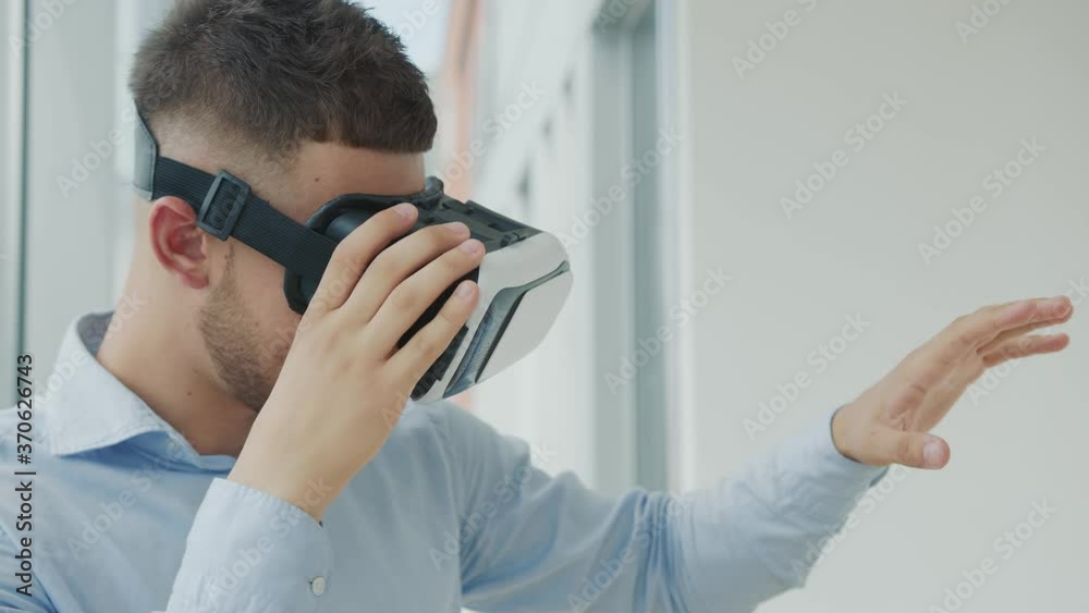 Close up Young man sitting at a desk in the office uses augmented reality glasses to work on business projects in various fields. Work in Virtual Reality
