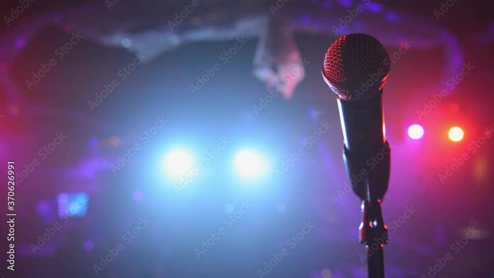 Sweeping close up of stage microphone under colorful spotlights 