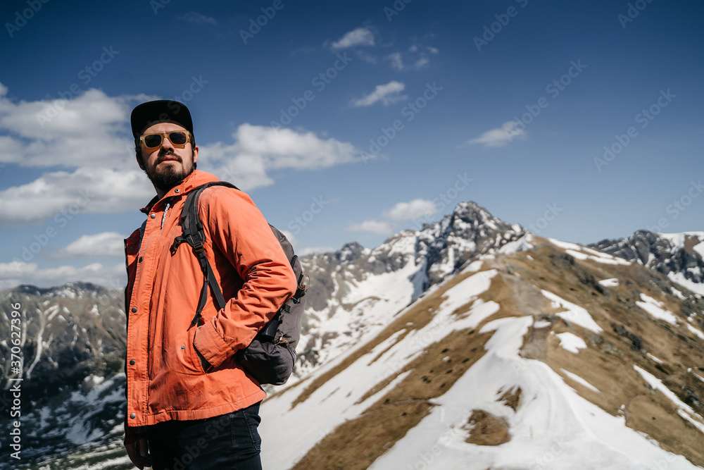  young hister guy with a beard in the mountains with a backpack. Active rest in one with nature