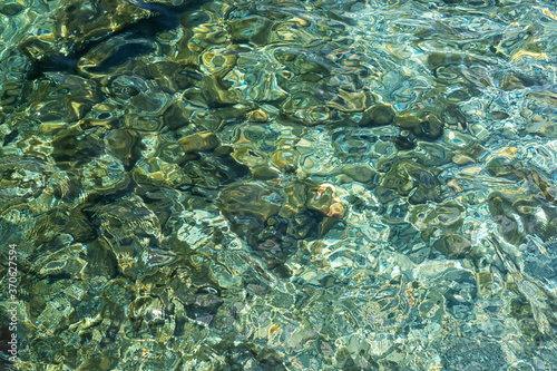 Abstract texture of clear turquoise sea water with a rocky bottom