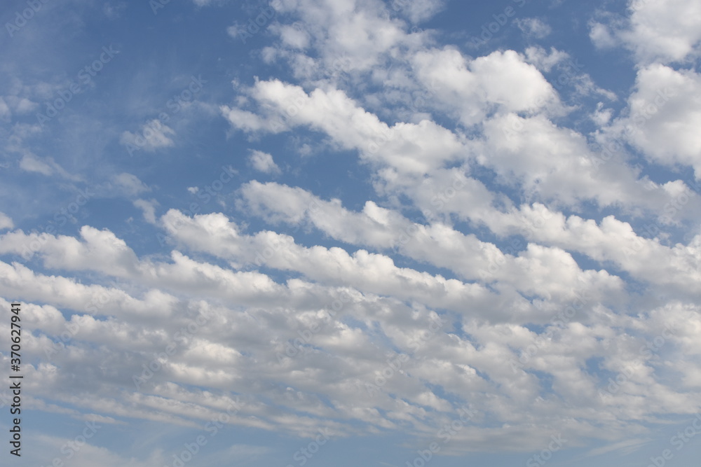 Azure blue sky with white cirrocumulus and alto cumulus woolpacks or heap clouds during sunny summer day over Swiss countryside. Azure blue sky with white cirrocumulus and alto cumulus woolpacks or heap clouds during sunny summer day over Swiss countryside.