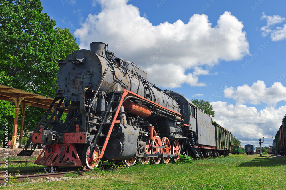 Naklejka premium Railway Museum in the town of Haapsalu. In the foreground is the old locomotive and the train station. Scene photographed in the autumn season. Estonia.