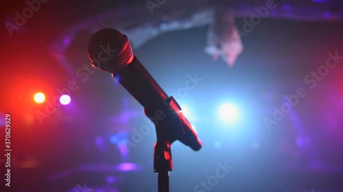 Sweeping close up of stage microphone under colorful spotlights 