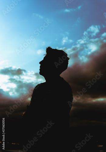 silhouette of young man among blue sky clouds