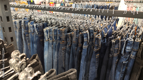 Jeans hang in a store on hangers in a row