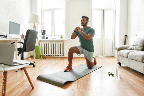 Stay motivated. Male fitness instructor showing exercises while streaming, broadcasting video lesson on training at home using laptop. Sport, online gym concept