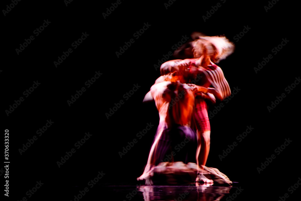 Obraz premium Blurred motion of dancers in contemporary dance performance with dark background