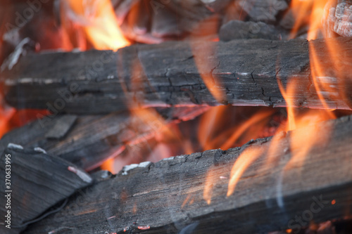 Close-up of burning firewood and coals in the old grill, selective focus
