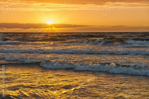 Sunset on Baltic Sea white bright golden orange color and rough sea