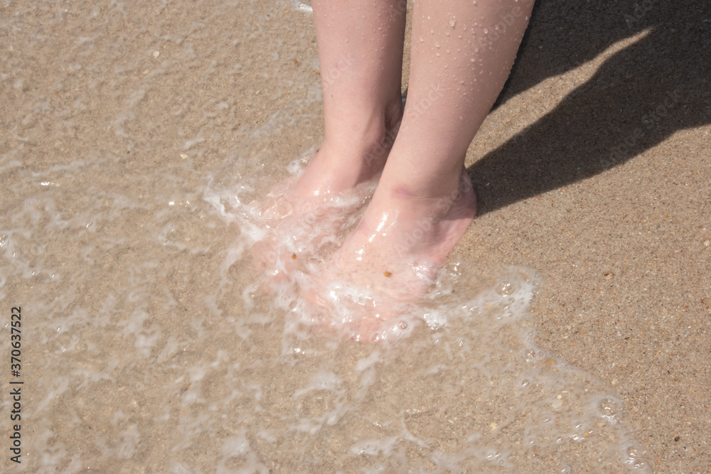 Waves rolling over feet on the beach Waves rolling over feet on the beach