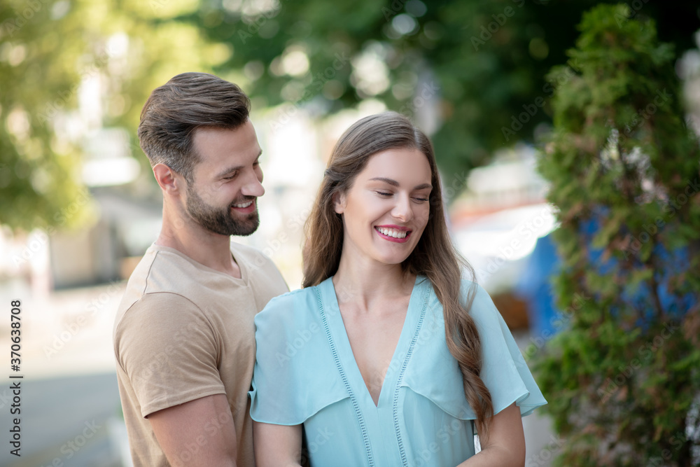 Bearded male hugging tenderly smiling female in blue dress Bearded male hugging tenderly smiling female in blue dress