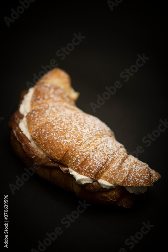 freshly plain croissant for breakfast with handmade cream and sugar on a black background, italian breakfast