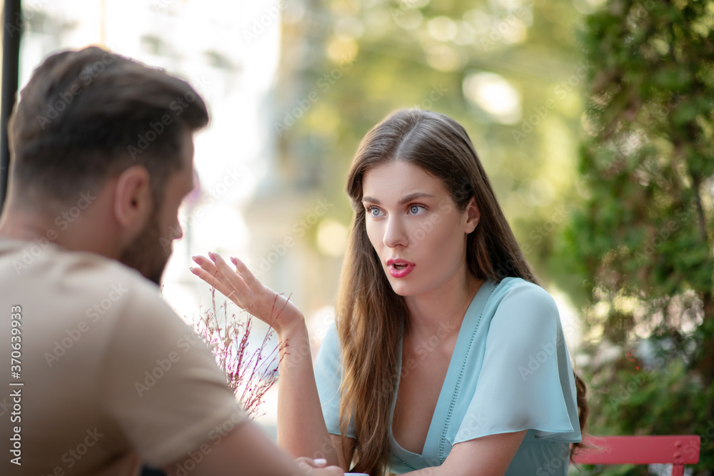 Sad couple sitting in open air cafe, arguing with each other Sad couple sitting in open air cafe, arguing with each other