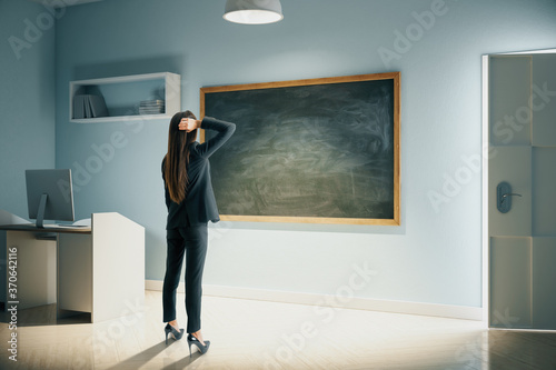 Businesswoman looking on blank blackboard.