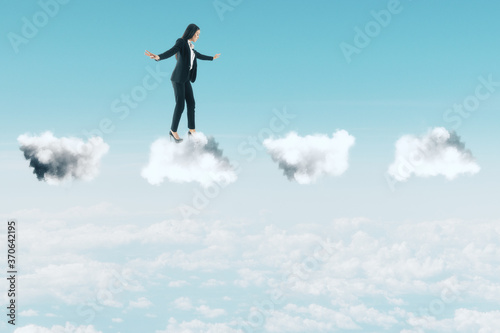 Businesswoman in suit standing on clouds
