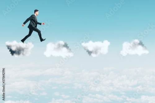 Young businessman walking on clouds.