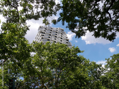 Modernes Apartmenthaus vor blauem Himmel mit weißen Wolken zwischen grünen Baumkronen im Sommer bei Sonnenschein an der Senckenberganlage in Bockenheim am Westend von Frankfurt am Main in Hessen photo
