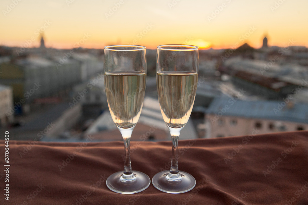 Two glasses of champagne on the background of city roofs at sunset