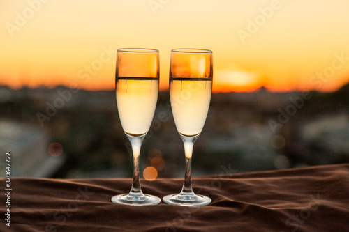 Two glasses of champagne on the background of city roofs at sunset