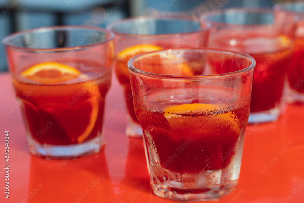 View of alcohol setting on catering banquet table, row line of red colored aperitif alcohol cocktails on a party, negroni and spritz, vodka, and others on decorated catering bouquet table event View of alcohol setting on catering banquet table, row line of red colored aperitif alcohol cocktails on a party, negroni and spritz, vodka, and others on decorated catering bouquet table event