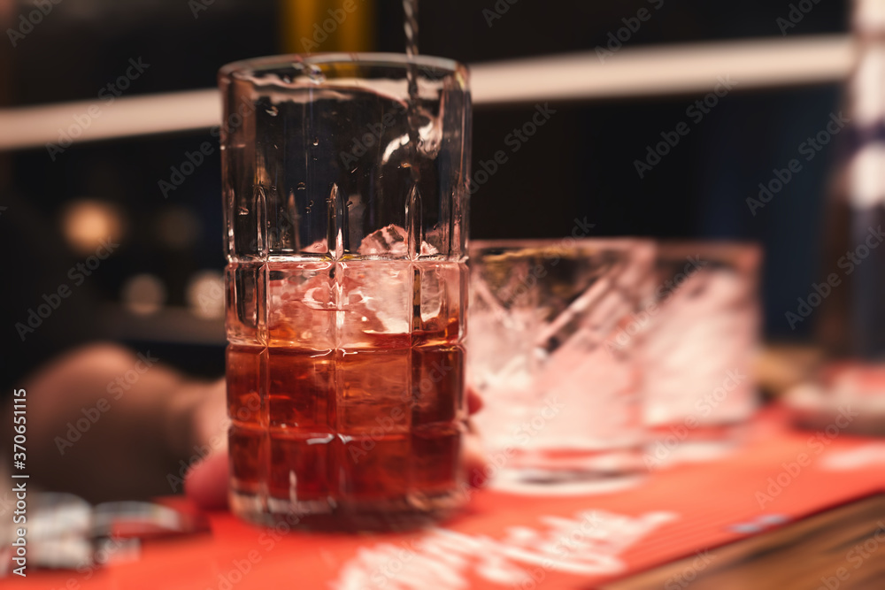 Row line of red colored negroni and spritz aperitif alcohol cocktails on a party of alcohol setting on catering banquet table, vodka, and others on decorated catering table event with bartender Row line of red colored negroni and spritz aperitif alcohol cocktails on a party of alcohol setting on catering banquet table, vodka, and others on decorated catering table event with bartender