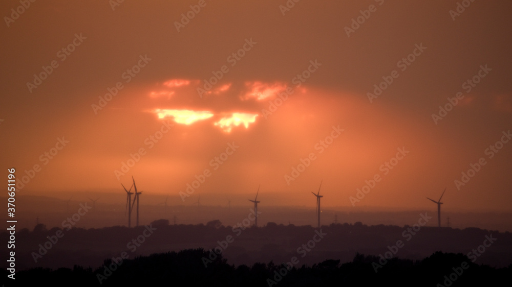 Sunset with wind turbines and dark orange sky, UK