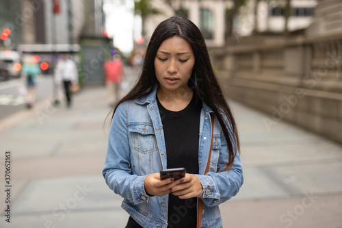 Young Asian woman walking street texting cellphone © blvdone