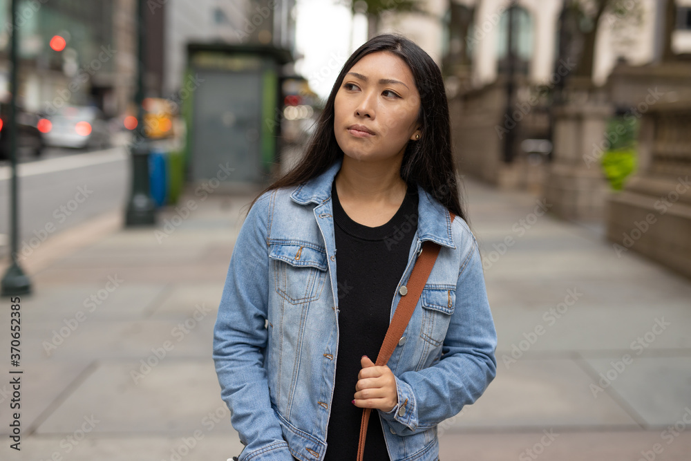 Fototapeta premium Young Asian woman walking city street serious face
