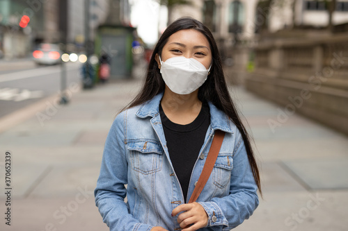 Young Asian woman wearing a mask walking street