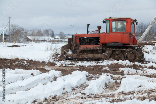 Vintage soviet tractor on dirty road with snow