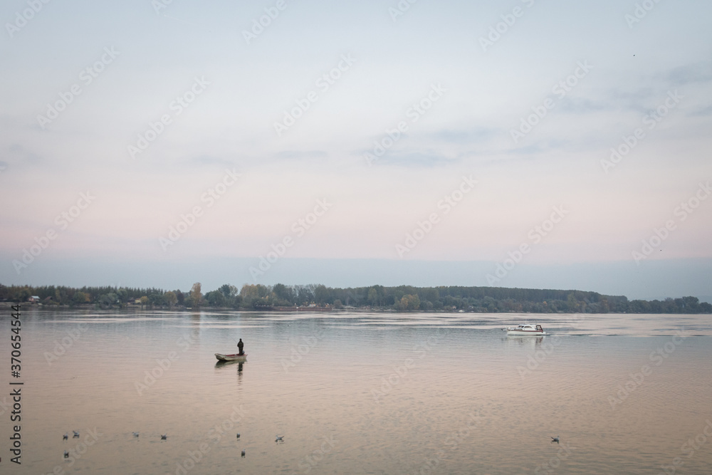 Fisherman boat fishing on the Danube river on his rowing boat during a warm autumn afternoon in Zemun, a northern district of Belgrade, capital city of Serbia.