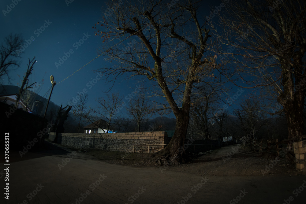 Full moon over quiet village at night. Beautiful night landscape of old town street with lights Full moon over quiet village at night. Beautiful night landscape of old town street with lights