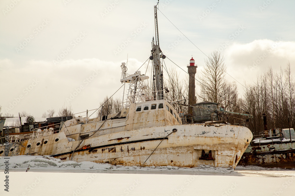Fototapeta premium Abandoned white ship frozen in ice near lighthouse